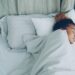 Young African American woman is sleeping in comfortable bed under warm blanket having rest on beautiful linen. Comfort, resting people and bedroom concept.