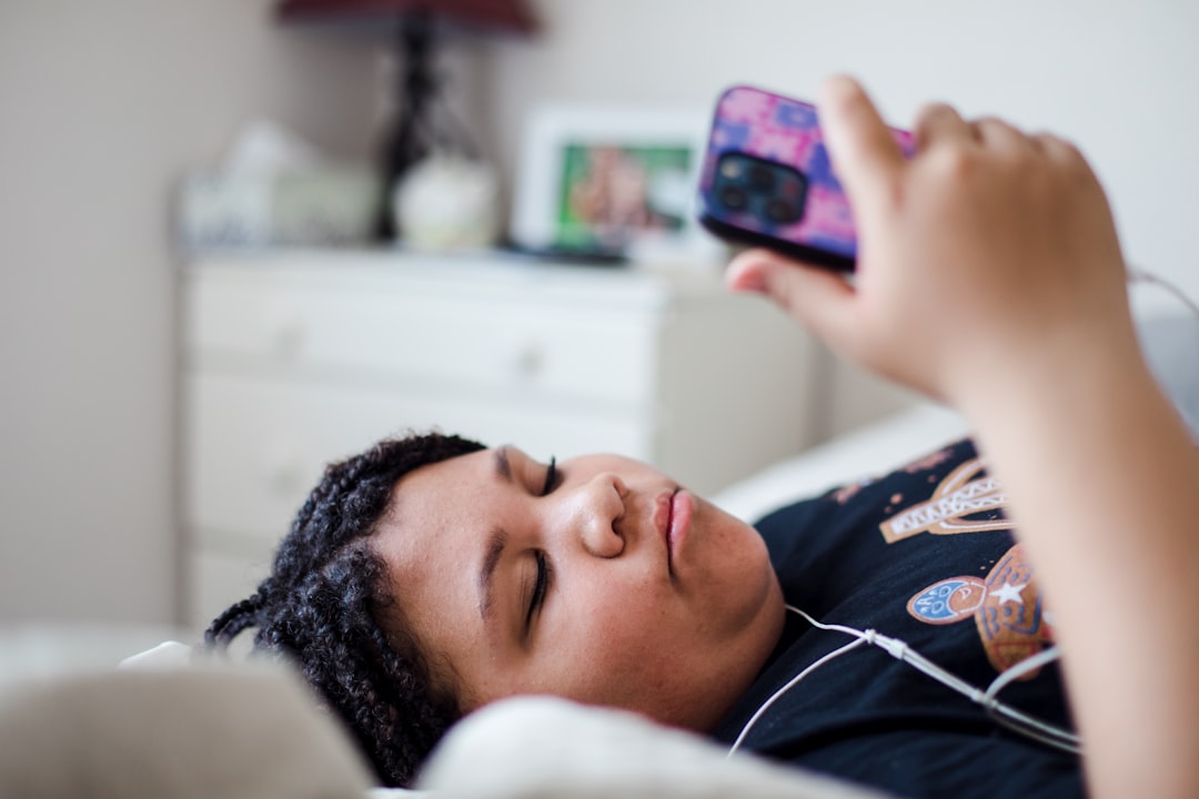 A girl laying on a bed with a cell phone